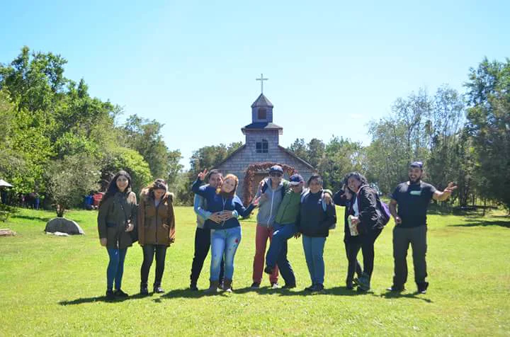 Nicolás junto a un grupo frente a una iglesia patrimonial de madera en Chiloé