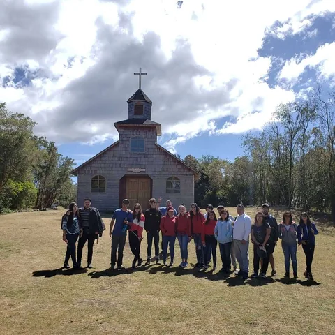 Grupo frente a la iglesia patrimonial de madera de Aucar, Chiloé